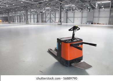 Electric forklift in large modern storehouse with some goods