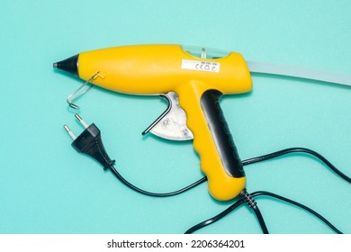 Electric Glue Gun On A Blue Background. A Tool For Gluing Various Parts Of Objects