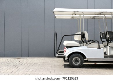 Electric golf cart back side view against gray concrete walls at car park.