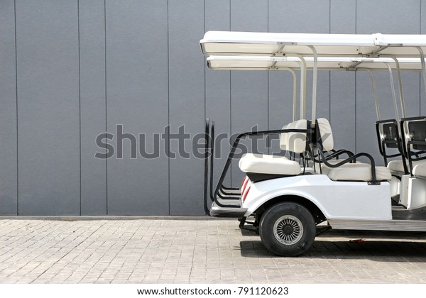 Electric golf cart back side view against gray\
concrete walls at car\
park.