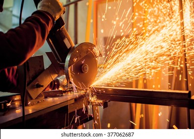 Electric grinder. A man working with electric grinder tool  on steel structure in factory, sparks flying