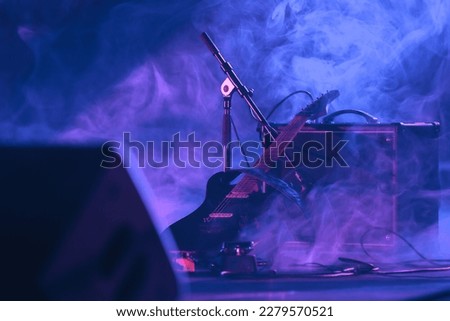 
electric guitar with its an amp in the dark on the stage of a concert with smoke and blue and pink lighting