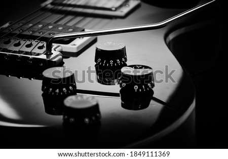 Electric guitar closeup and isolated on black background. Musical instrument in black and white with tremolo and details.