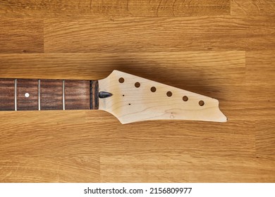 Electric guitar craft workshop, neck and headstock with bare wood surface, no strings or tuners attached