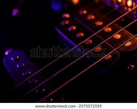 Electric guitar strings close up. Musical instrument details. Concert color contrast lighting. Six-string guitar during performance. Bright colors on dark background. Cinematic light. Copy space