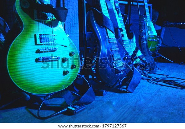 Electric guitars before the concert stand\
on stage on stands under the light of\
spotlights.