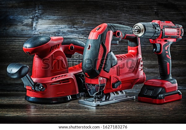 electric hand tools red\
corded jigsaw cordless drill and speed variable power small plunge\
router milling machine portable mini wood router on vintage wooden\
background