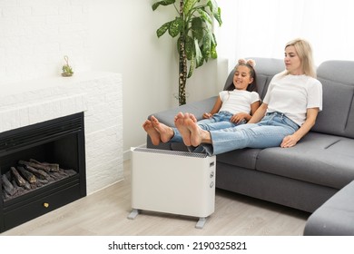 Electric heater at home. Young family warms his frozen hands near a heating radiator