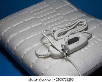 Electric heating pad on a blue background. Comfort and health. Heating pad with temperature and time control options - Shutterstock ID 2105762285
