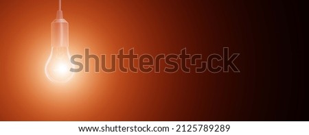 electric incandescent lamp on a black background with an orange halo