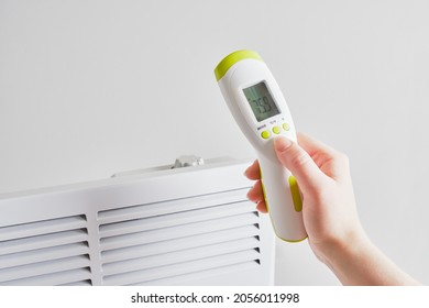 electric infrared thermometer for measuring surface temperature and air on the background of electric radiator, heating season concept, indoor air temperature - Powered by Shutterstock