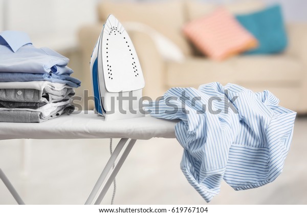 Electric iron\
and pile of clothes on ironing\
board