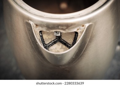 An electric kettle with limescale. In hard water area, region. Top view. Selective focus. Close up of the teapot spout with traces of limescale