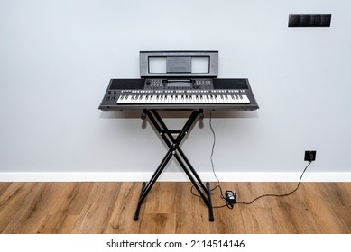 Electric keyboard for playing and mixing music standing on a stand by the wall in the room.