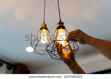 Electric LED Lightbulb Change In Light At Home. Decorative antique edison style filament light bulbs hanging. An electrician is installing spotlights on the ceiling