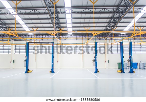 The electric lift for cars in the service\
put on the epoxy floor in new car factory service , Car repair\
service center blurred  background for industry\
