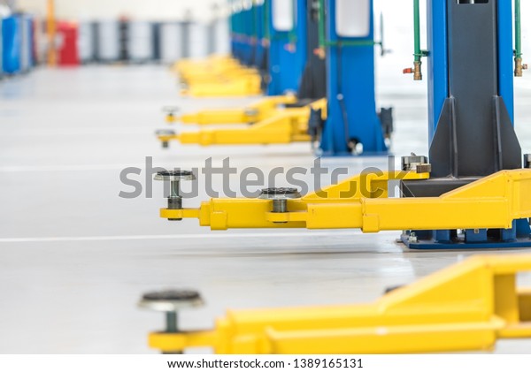 The\
electric lift for cars in the service put on the epoxy floor in new\
car factory service ,  blurred background for industry , Car lifted\
in automobile service for fixing , yellow\
lift
