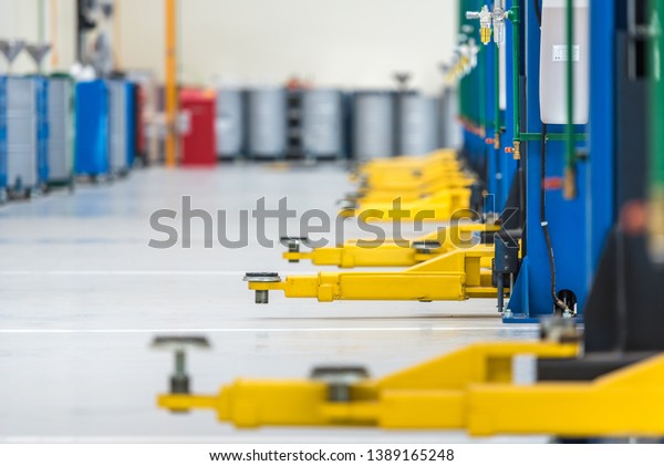 The\
electric lift for cars in the service put on the epoxy floor in new\
car factory service ,  blurred background for industry , Car lifted\
in automobile service for fixing , yellow\
lift