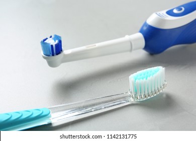 Electric and manual toothbrushes on gray background