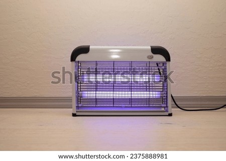 Electric Mosquito and Insect Zapper With Blue Purple Lights Turned on. Bug Killer Lamp on Wooden Floor in Room. Fly Trap for Outdoor and Indoor. Horizontal Plane . High quality photo