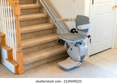 An electric, motorized chair lift for persons with disabilities on a carpeted staircase in a residential home.