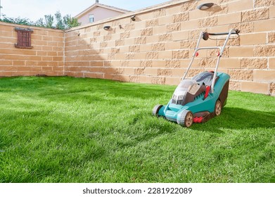 Electric mower machine trimming green lawn of home garden. Backyard lawn maintenance concept. - Shutterstock ID 2281922089