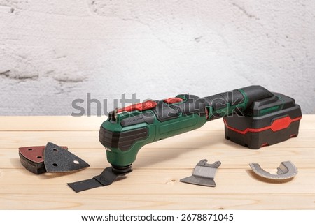 Electric multifunction oscillating tool with accessories on a wooden table. Selective focus.