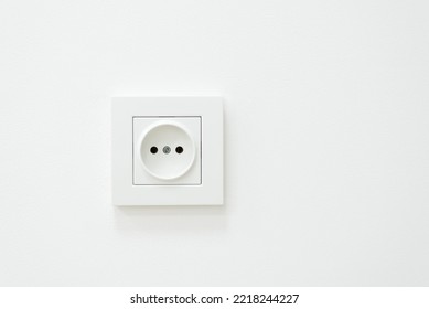 Electric outlet on a white wall. White inked wall with electric socket - Shutterstock ID 2218244227