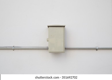 Electric pipe and control box on white wall.