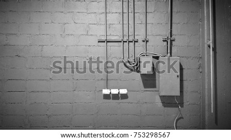 Electric pipeline and service box on cement wall as industrial background 