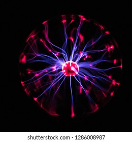 Electric plasma globe with blue energy filaments striking inner surface of glass globe causing red glow.