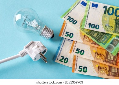 Electric plug, light bulb and euro money banknotes over blue background. Increasing of electricity cost for residential and business users, expensive energy bill and rise in electricity prices concept