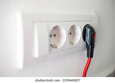 Electric Plug. Electric Socket. Black Power Cord Cable Plugged Into European Wall Outlet On White Plaster Wall With Copy Space. 