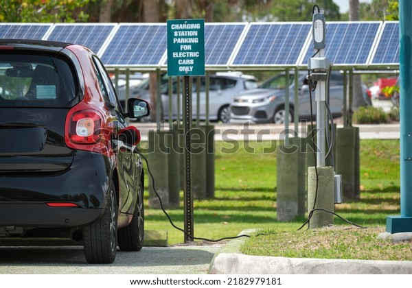 Electric plug-in car\
charging with electricity from solar renewable power source parked\
on city street