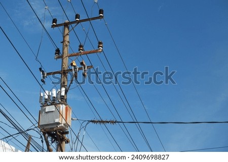 Electric pole with AC high-voltage power transformer against blue sky background