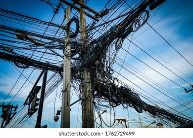 An electric pole with tangled wires in an Asian style. The chaos of electric wires in Phuket, Thailand.