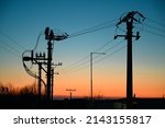 Electric poles with power lines at sunset. Electricity transmission.