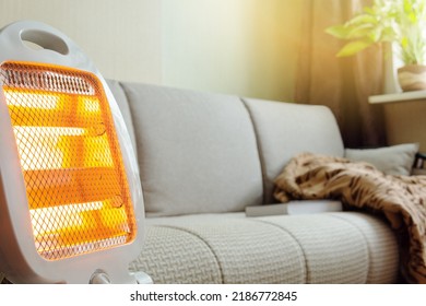 The electric portable heater is on in the room next to the couch. - Shutterstock ID 2186772845