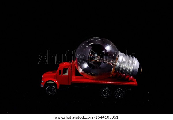 Electric Power Concept Red Truck and Light\
Bulb on a Black\
Background
