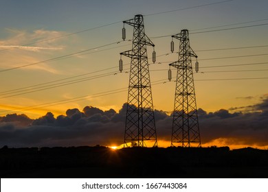 Electric power industry and renewable energy. Transmission towers or electricity pylons with solar energy behind