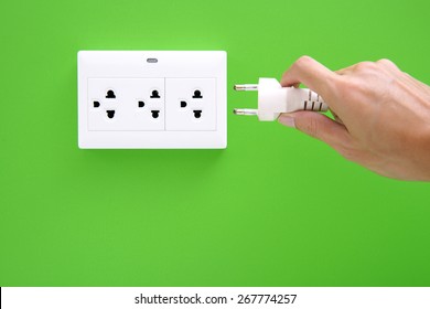 Electric Power Plug In A Hand And Inserting Into Power Wall Socket