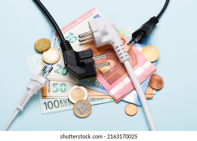 Electric power plugs on Euro banknotes on blue background. Concept of expensive electricity costs and rise in energy bill prices.