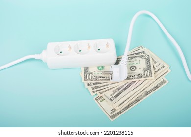 Electric Power Strip Extension Cord And US Dollar Bill Banknotes On Light Blue Background. Rising Electric Price And Expensive Energy Concept