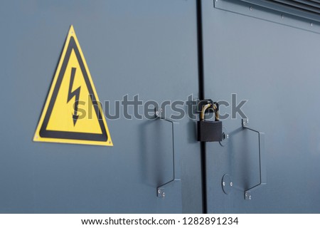 Electric power substation with attention sign. Closed lock