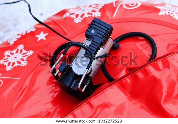 Electric pump with monometer pumping\
air into tire of tube on winter day. Equipment,\
device.