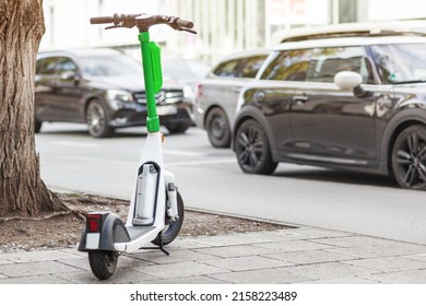 Electric Ride Sharing Scooter. Dockless scooter for rent on street on background of cars. Urban bicycle transport