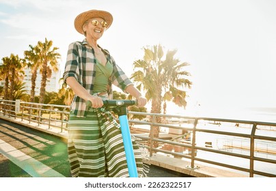 Electric scooter, happy and senior woman on a vacation, weekend trip or adventure on beach promenade. Happiness, freedom and elderly lady in retirement having fun while on summer holiday in Australia - Powered by Shutterstock