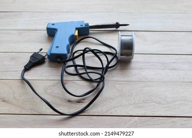 Electric Soldering Iron With Lead Solder Isolated On Wooden Background Closeup.