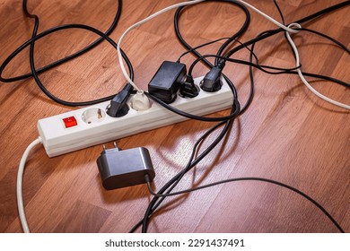 Electric splitter with lots of plugged sockets, concept of increasing power consumption and growing electricity demand, too many electrical devices