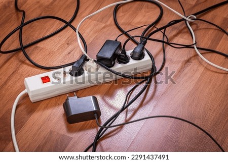 Electric splitter with lots of plugged sockets, concept of increasing power consumption and growing electricity demand, too many electrical devices